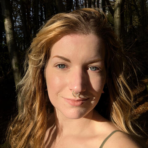 Image of Carli, birth doula, in the woods with the sun on her face